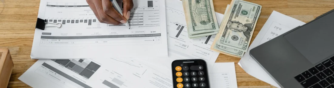 Financial professional reviewing reports with a laptop and calculator